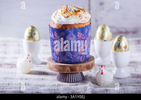 Easter cake, chocolate eggs in gold foil and chicken-shaped candles on a light background. Stock Photo