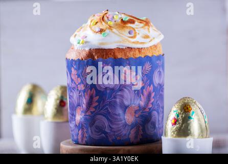 Easter cake, chocolate eggs in gold foil and chicken-shaped candles on a light background. Stock Photo