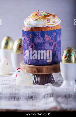 Easter cake, chocolate eggs in gold foil and chicken-shaped candles on a light background. Stock Photo