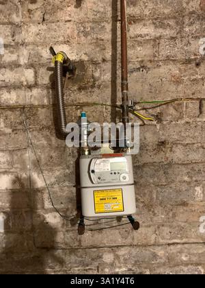 Gas meter in a cellar Northampton England UK British old style type wall pipes pipe fitted on a wall dirty aged pipework bricks brick dial shadow Stock Photo