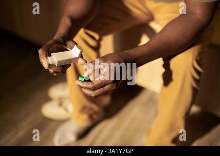 High angle of hands of mature man holding asthma inhaler while suffering from attack after getting nervous on sleepless night Stock Photo