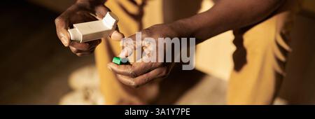 Header of hands of mature man holding asthma inhaler and its green cover while suffering from attack on sunny morning Stock Photo