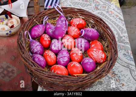 Wicker basket is filled with hand decorated traditional Hungarian folk art design. Flower patterns, red, purple, and white easter eggs. Stock Photo