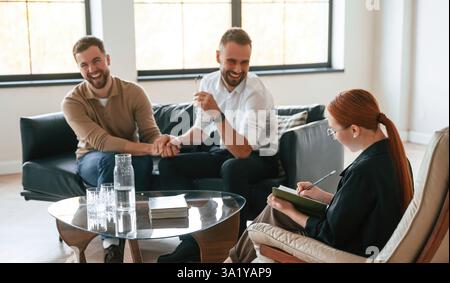 Holding hands, happy. Gay couple at a psychologist's appointment. Stock Photo