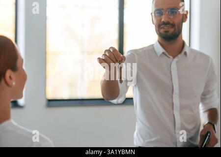 Realtor is standing and holding keys for new apartment to the woman. Stock Photo