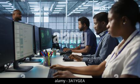Cybersecurity specialists in server room trying to protect equipment from hacker stealing data. Programmers in data center office doing teamwork to delete virus attacking company servers, camera A Stock Photo