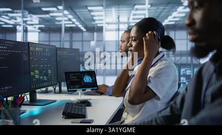 Data center engineer wearing headphones enjoying songs, maintaining company network infrastructure. Woman in server hub listening music while ensuring optimal system performance, camera A Stock Photo