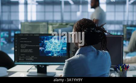 Engineer typing on computer in server hub, monitoring data center energy consumption using AI software. Technician inspecting rackmounts in server room using artificial intelligence tech, camera A Stock Photo