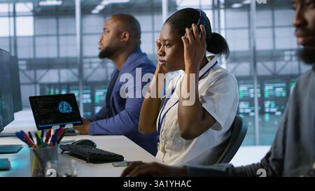 Woman putting headphones on in server room, developing disaster recovery plans ensuring minimal downtime. Engineer listening music in data center, using data analytics to monitor performance, camera A Stock Photo