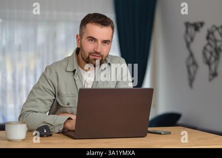 A happy man using a laptop while working at home office. Stock Photo