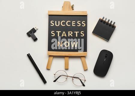 Blackboard with text SUCCESS STARTS NOW, computer mouse and flash drive on white background. Top view Stock Photo