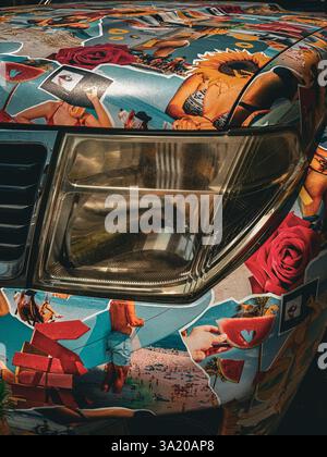 Pop-art car with eccentric collage design A close-up of the front of a vehicle fully covered in colorful, eclectic collage art. The vibrant aesthetic Stock Photo