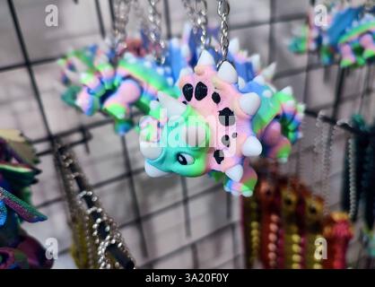 Objects keychains in form of models of toys colorful dinosaur printed on 3D printer from multi-colored molten plastic hanging on chain closeup. Concept 3D Printing. New 3D Printing additive technology Stock Photo