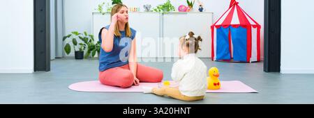 Nonverbal child with Down syndrome learning baby sign language with the help of a speech therapist. Child therapy, neurodiversity, learning difficulty Stock Photo