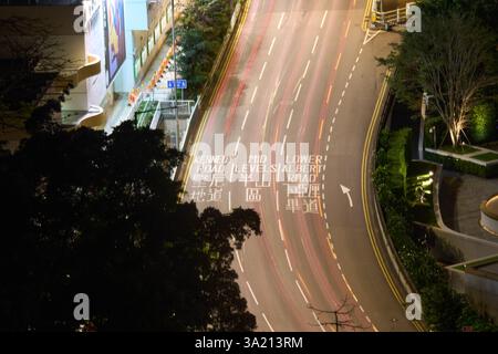 Light trails on location name writings in English and Traditional Chinese on Cotton Tree Drive at night, Hong Kong Island Stock Photo