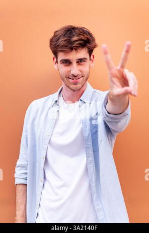 young man holding up two fingers in victory sign Stock Photo