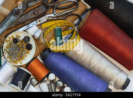 Sewing needles stuck in a green miniature spools thread Steel scissors, Spools of thread of various colour, Thimbles and Measuring tape including Pins Stock Photo