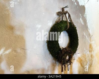 Green moss wreath featuring a bird's nest, displayed against a textured wall setting. Stock Photo
