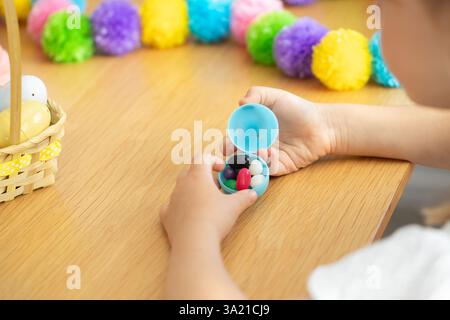 Child opening easter egg with colorful candy surrounded by festive decorations for spring celebration. Easter.  Stock Photo