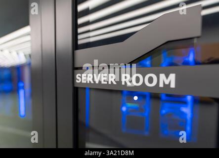 Glass door with server room sign and illuminated data center equipment in the background Stock Photo