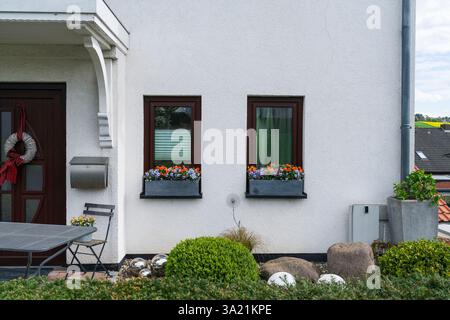 Cottage windows with flowers on the windowsill in a European village Stock Photo