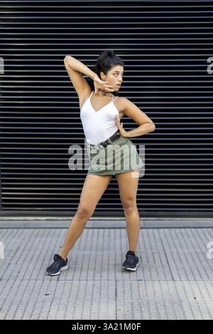 Confident young woman dancing against a modern backdrop Stock Photo