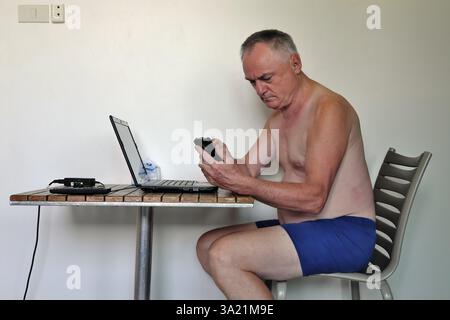 Businessman, freelancer, 60 plus on holiday working with laptop and mobile phone, Pattaya, Chonburi, Thailand, Asia Stock Photo