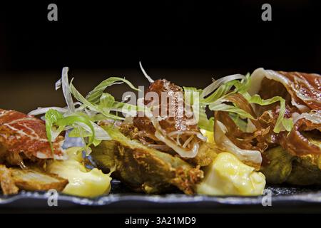 Roasted artichoke hearts with slices of raw ham, jamon de bellota Stock Photo