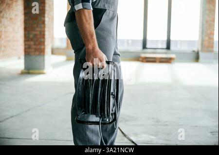 Holding wires. Close up view of repairman indoors in unfinished building. Stock Photo