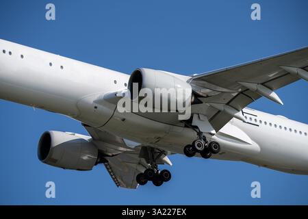 Modern commercial aircraft landing at international airport against blue sky showcases powerful jet engines and aerodynamic design during peak summer Stock Photo