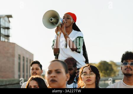 A diverse group of individuals engaged in a public demonstration, with a woman passionately addressing the group using a megaphone, exemplifying activ Stock Photo