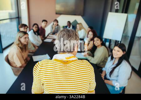 A small class with diverse students engaged in learning. A teacher leads the discussion in a bright, modern environment, promoting education and inter Stock Photo