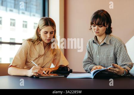 Focused scene of two students collaborating in a university library. They engage in study and teamwork in an urban education environment. Stock Photo