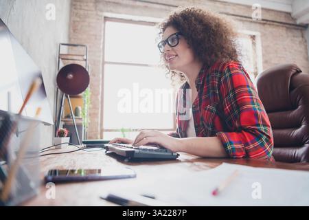 Freelance programmer working at a stylish home office desk wearing a casual checkered shirt, enjoying a productive and creative workspace Stock Photo