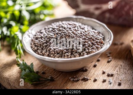 Raw lentils in bowle with parsley herbs on kitchen table. Stock Photo