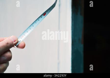 a hand holding the end of measuring tape, outdoor close-up Stock Photo