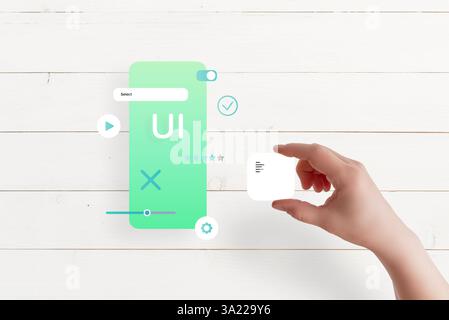 Top view of hand assembling app interface on table, placing text box, concept of UI/UX design and mobile app development Stock Photo