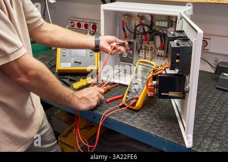 Technician Testing Electrical Equipment Using Multimeter and Professional Tools Stock Photo