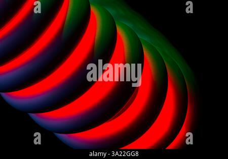 a curly plastic covered monitor cable, artistically illuminated with red and green lighting Stock Photo