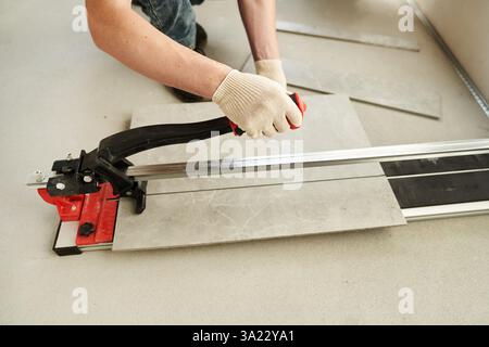 A close-up of the hands of a master who divides time into two parts using a machine. An installation for cutting large ceramic tiles into smaller ones with precise dimensions. High quality photo Stock Photo