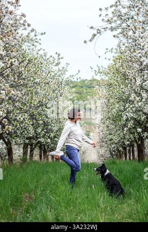 Woman is doing exercising and stretching during dog walking with her border collie outdoors Stock Photo