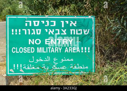 Warning sign indicating restricted military area written in Hebrew, English and Arabic languages. Military area, keep out, no entry warning sign on mi Stock Photo