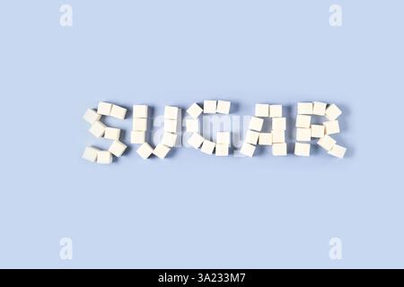 Arrangement of white sugar cubes forming the word 'sugar' on light blue background. Stock Photo