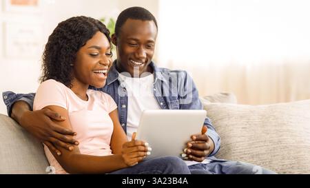 Smiling african man and woman websurfing together at home Stock Photo
