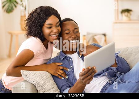 Cheerful black couple using digital tablet at home Stock Photo