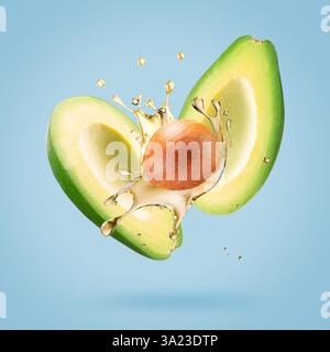 avocado with oil splash on a light blue background. Stock Photo