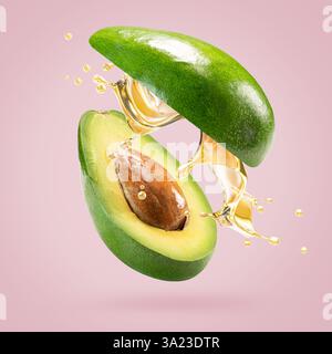 avocado with oil splash on a light pink background. Stock Photo