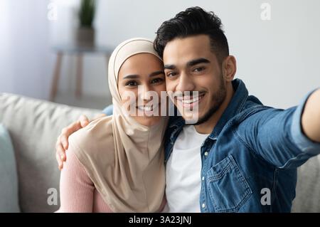 Beautiful muslim man and woman in hijab taking selfie Stock Photo