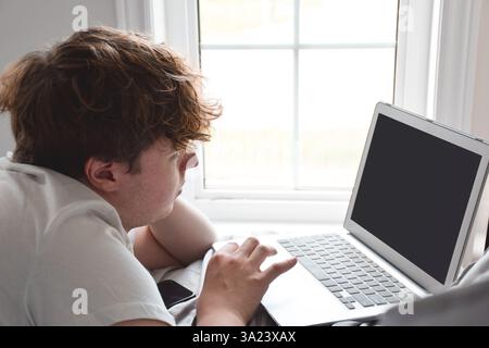 Young man laying on bed using laptop computer Stock Photo