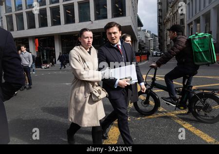 A young couple walk arm in arm across Bishopsgate during the midday lunch period, as workers enjoy some Spring sunshine, City of London, England, UK Stock Photo